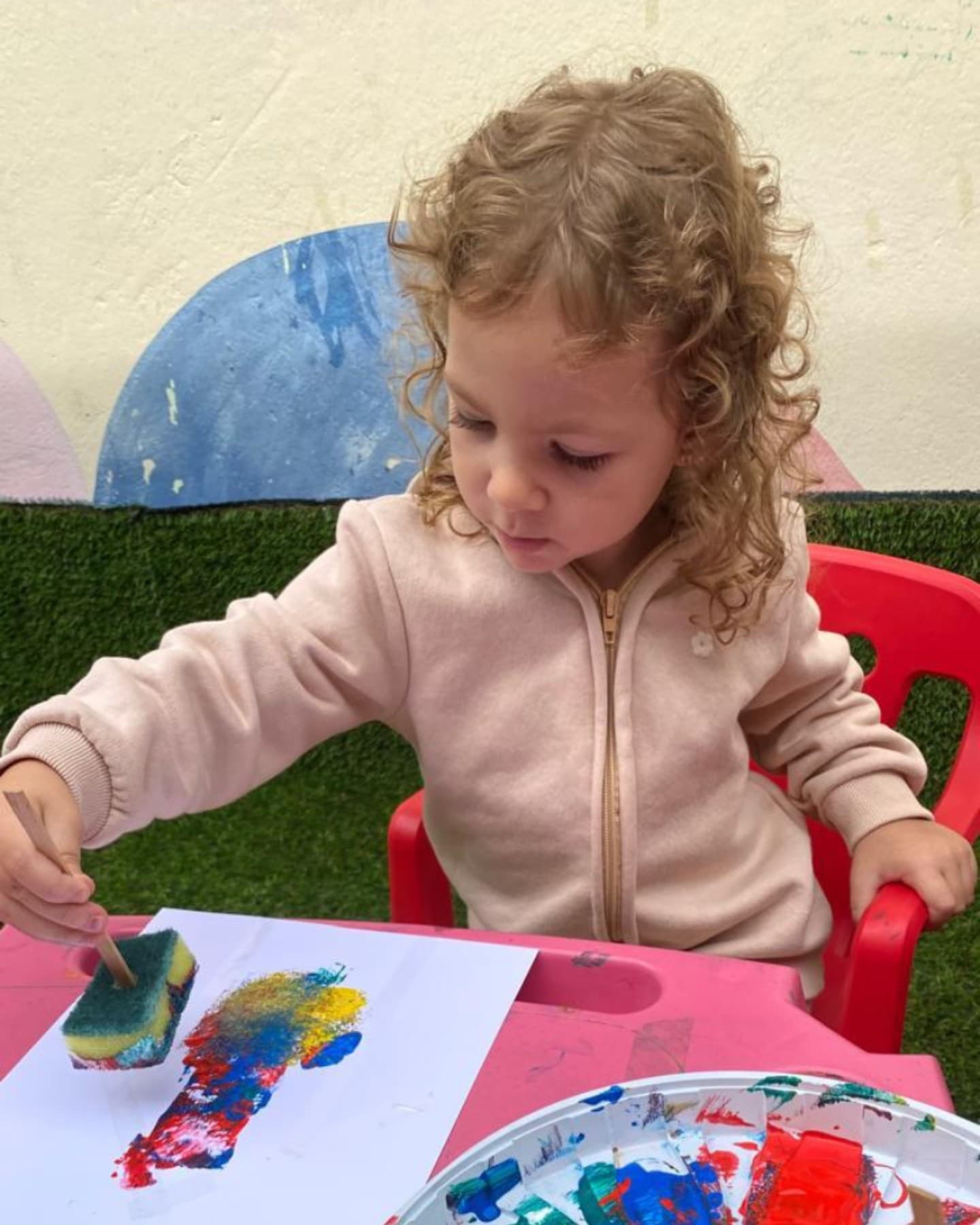 Menina pintando com esponja e tinta colorida