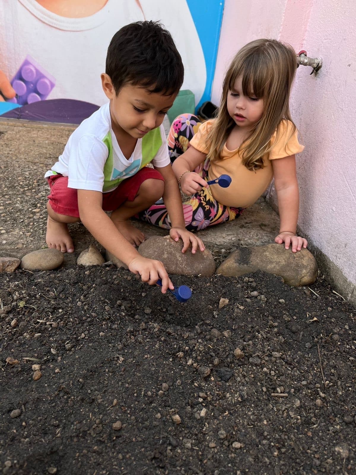 Duas crianças agachadas brincando na terra